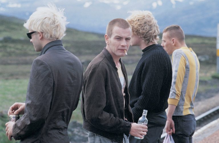 Four main characters on a train platform in the Scottish countryside in the film Trainspotting (1996)