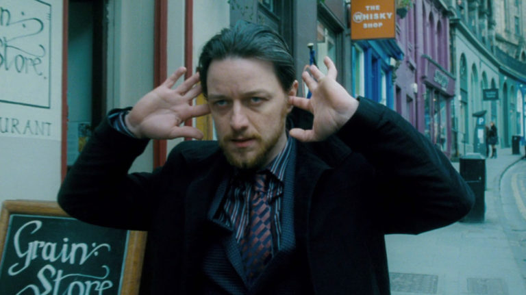 James McAvoy walking down Victoria Street in Edinburgh with his fingers in his ears in the film Filth (2013)