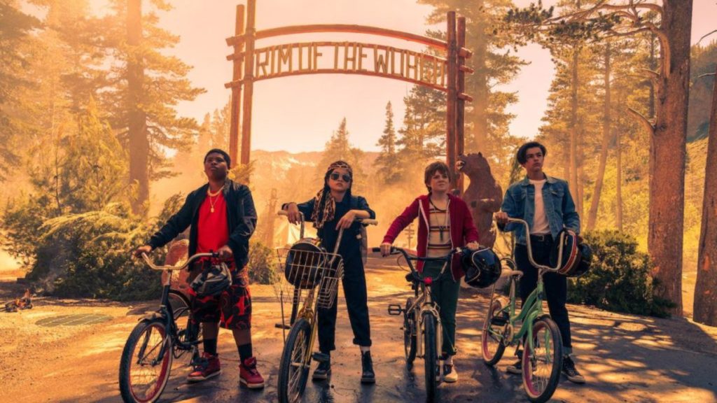 Rim of the World (2019) film still with four children on bikes outside the camp's sign