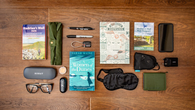 Flat lay of a notebook, guide book and other accessories for a Hadrian's Wall Path packing list