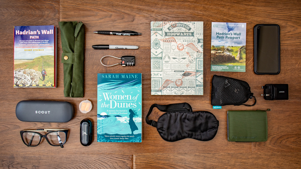 Flat lay of a notebook, guide book and other accessories for a Hadrian's Wall Path packing list