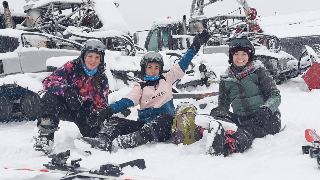 Almost Ginger blog owner with two friends sat in the snow wearing ski gear in Switzerland